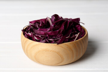 Fresh chopped red cabbage in wooden bowl on white table