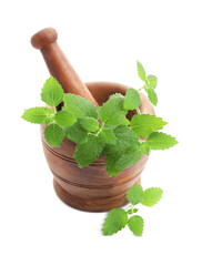 Wooden mortar with pestle and fresh green lemon balm leaves isolated on white