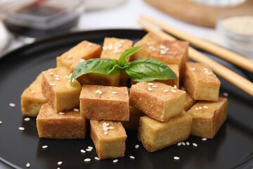 Plate with delicious fried tofu, basil and sesame seeds, closeup