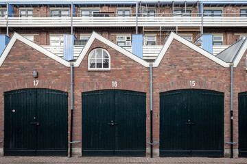 Outdoor street view in front of exterior garage entrance with wooden green doors, brick facade and...