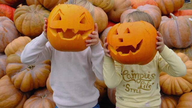 4K Children holds a empty sinister pumpkin in hands on Halloween day against the pumpkins background.