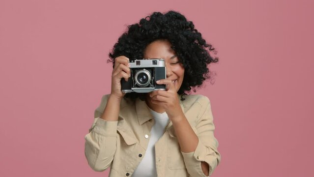 Portrait African American girl posing for camera taking photo wearing casual denim beige jacket smiling on road trip adventure at pastel pink studio background. Positive tourist with Afro hairstyle 4K