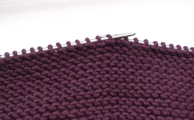 Purple knitted fabric on knitting needles