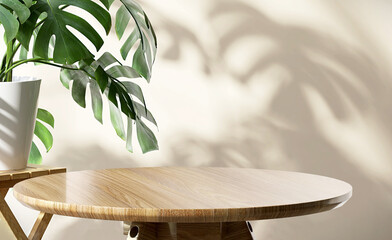 Wooden round side table with green tropical plant leaf and beautiful sun light and shadow on beige...