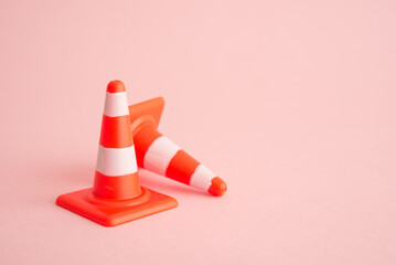 Attention, under construction, maintenance or repair concept. Close up single orange white traffic warning cone or pylon on pink background with copy space.