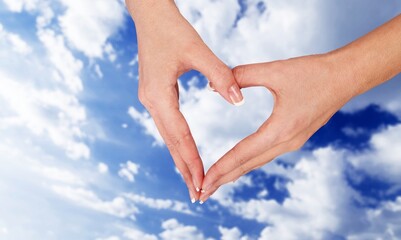 Human hands in the form of heart against the sky. Hands in shape of love heart. Love, friendship...