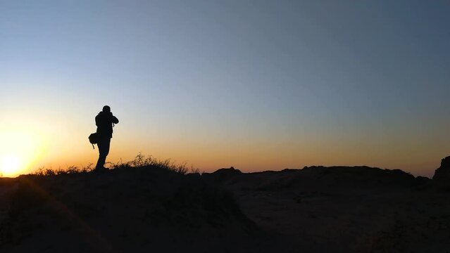 The photographer is silhouetted at sunrise