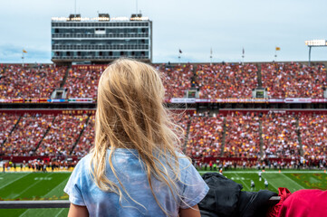 Caucasian girl looking at blurred background of football game