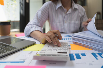 accounting concept. businesswoman working using calculator with money stack in office