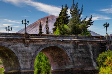 The famous Puente Grau Bridge in Arequipa in Peru with the snowless Misti Volcano in the background.