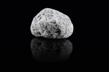 An untreated piece of pumice stone with a light gray porous surface