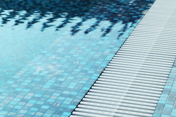 Close-up of the pool edge in blue mosaic tiles. Clear blue water in the pool. Relax in the backyard of a country house