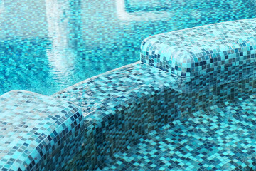Close-up of a blue mosaic in a beautiful swimming pool. Clear blue water in the pool. Relax in the backyard of a country house