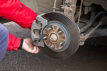 A man replaces the brake pads on a car. Security, service. - obrazy, fototapety, plakaty
