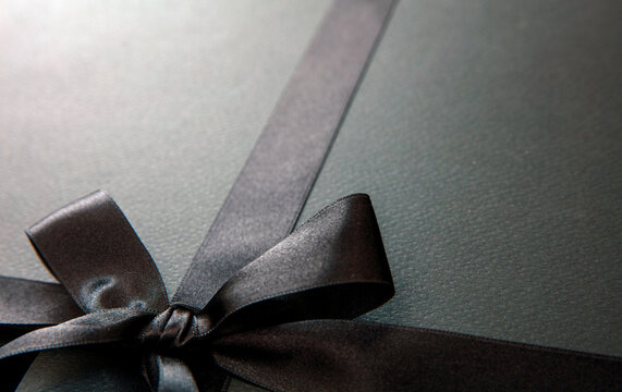 Black Friday Sale and Christmas gifts concept. Black satin ribbon and bow tied, close up