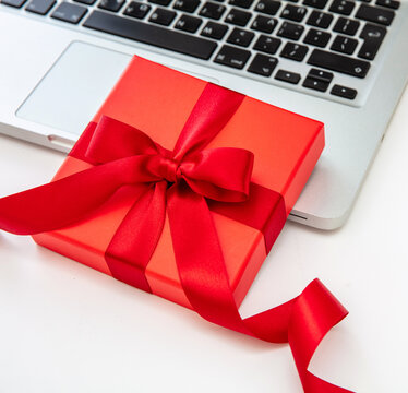 Red gift box on computer laptop, white background, close up