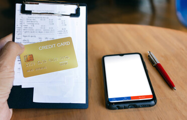 Close up view, hand holding cradit card with receipt on clamp board and mobile phone, Credit card debt and expenses paying concepts