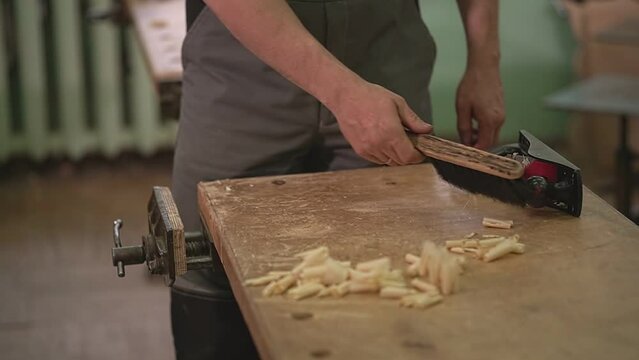 the master sweeps the chips with a brush after processing the wood from the table. slow motion video