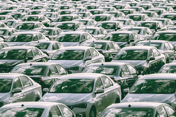 Rows of a new cars parked in a distribution center on a car factory on a sunny day. Top view to the...