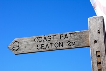 Wooden coastal path sign for Seaton against a blue sky, Beer, Devon, UK, Europe. - 543357407