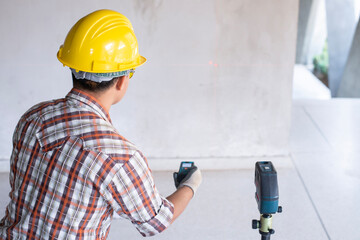 Worker in  measuring wall with laser leveler at construction site, Engineers at work checking construction building project with laser level machine during measurement work on site