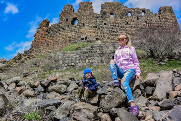 A girl with a child on the background of the 7th-century Amberd fortress, located on the slopes of...
