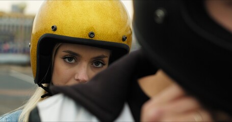 Close-up portrait of a young attractive girl sitting on a motorcycle behind her boyfriend. Couple...
