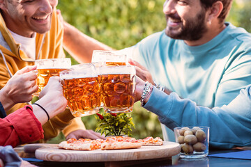 Cheerful group of young people clinking mood glasses over a sliced pizza