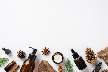 Organic skincare cosmetics concept. Top view photo of amber glass bottles fir branches pine bark...