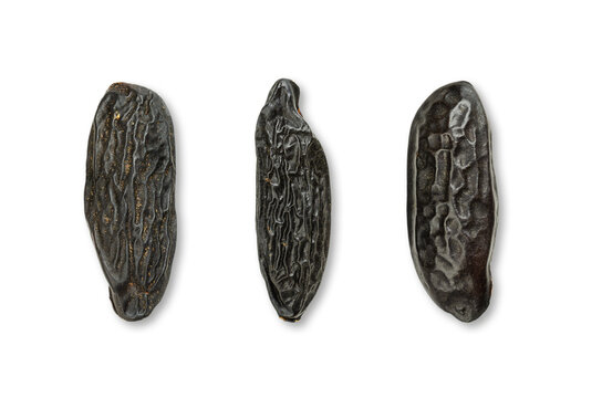Three tonka beans, close-up, from above, on white background. Tonkin or tonquin beans, black and wrinkled seeds of the tree Dipteryx odorata. Natural coumarin fragrance, used in cuisine and perfumes.