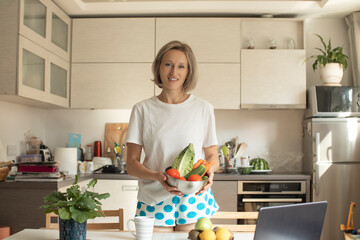 young positive smiling woman with vegetables in the kitchen
