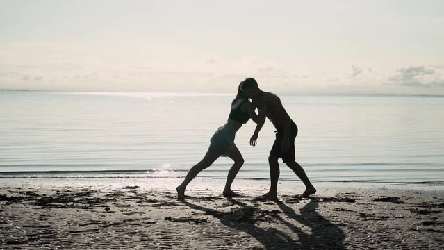 Couple on beach pushing each other, harmony or reconciliation after fight, silhouettes view