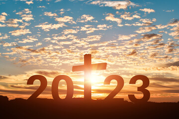 Silhouette of Christian cross with 2023 years at sunset background. Concept of Christians new year...