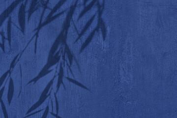 Shadow of leaves on blue concrete wall texture with roughness and irregularities. Abstract trendy...