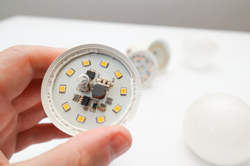 Repairman hand holding the broken white LED lamp, isolated on white background. Broken white led...