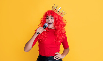 smiling kid in crown with microphone on yellow background