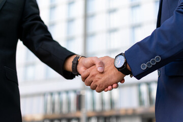 Partners greeting each other in business district. Business man and woman in office suits shaking hands outside. Handshake closeup concept
 - obrazy, fototapety, plakaty
