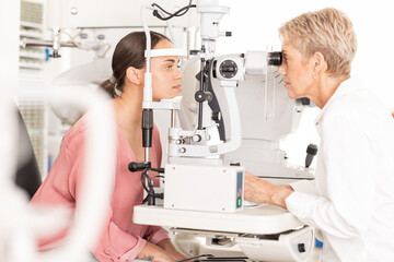 Eyes, doctor and eye exam by woman consulting ophthalmologist for vision, eye care and sight at clinic. Optical, exam and eye health by women in a consultation room for optometry, check and diagnosis - obrazy, fototapety, plakaty