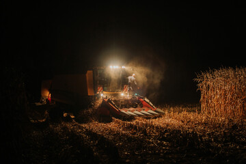 Żniwa w nocy,  rolnik wychodzi z kombajnu do kukurydzy - obrazy, fototapety, plakaty