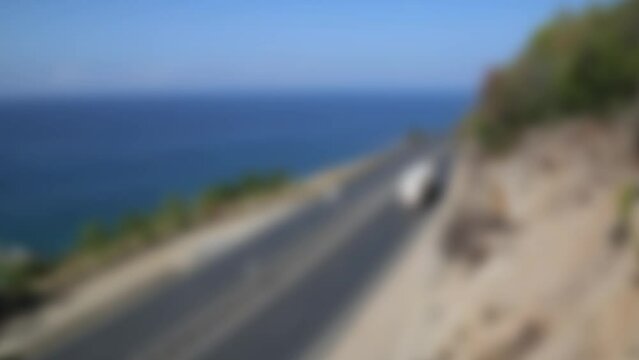 A busy highway with traffic in a picturesque place by the sea, Blurred image, out of focus.