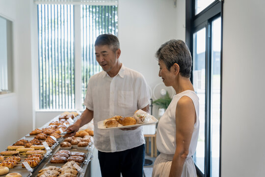 パン屋でパンを選ぶ日本人シニア夫婦