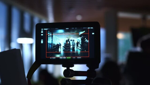 Staff communicates and works at semi dark filming set in pavilion view via camera screen. Preparation for shooting