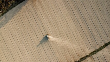Fototapeta premium Aerial view of tractor extruding ground to compact soil levelling rural field