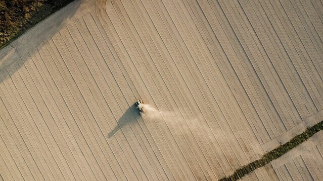 Aerial view of tractor extruding ground to compact soil levelling rural field