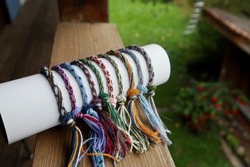 Multicolored handmade kumihimo bracelets on the background of the balcony overlooking the garten.
