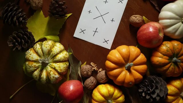 Blank sheet of paper with tracking markers lies among autumn vegetable composition in closeup filmed from above. Top view of mockup card framed by pumpkins and apples. Harvest seasonal festival theme.