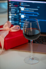 glass of wine with gift box in front of laptop online dating