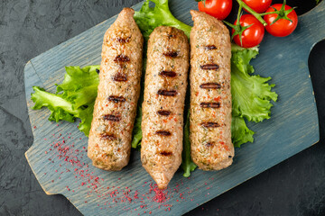 Juicy lula kebab made from soy meat cooked on the grill. Vegetarian kebab, sausages and vegetables on a dark table.