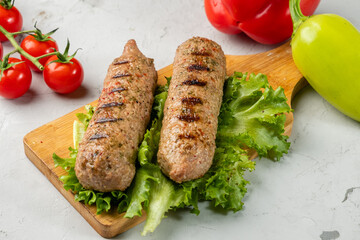 Grilled soy meat sausages on a light background and on a wooden board.