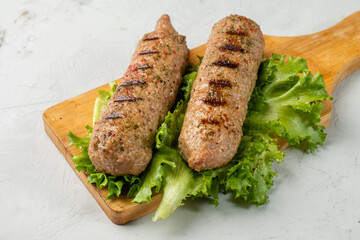Grilled soy sausages. Vegetarian barbecue. Wooden board and light background.